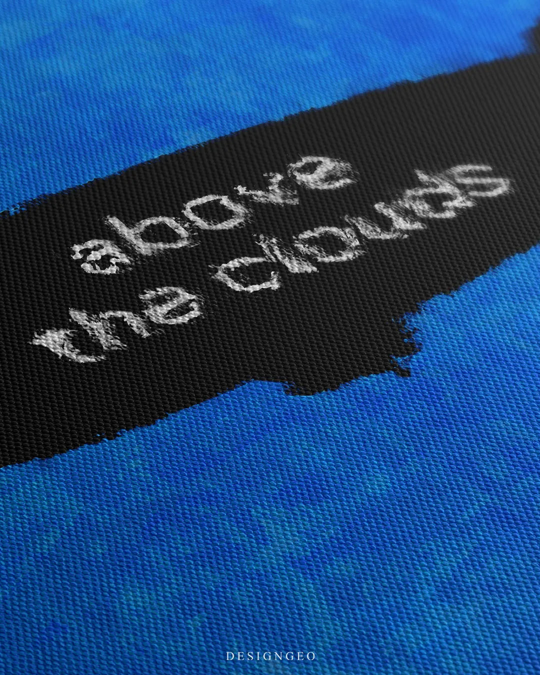 Angled macro detail of blue canvas wall art highlighting the woven fabric grain and white printed text ABOVE THE CLOUDS on a black zeppelin silhouette