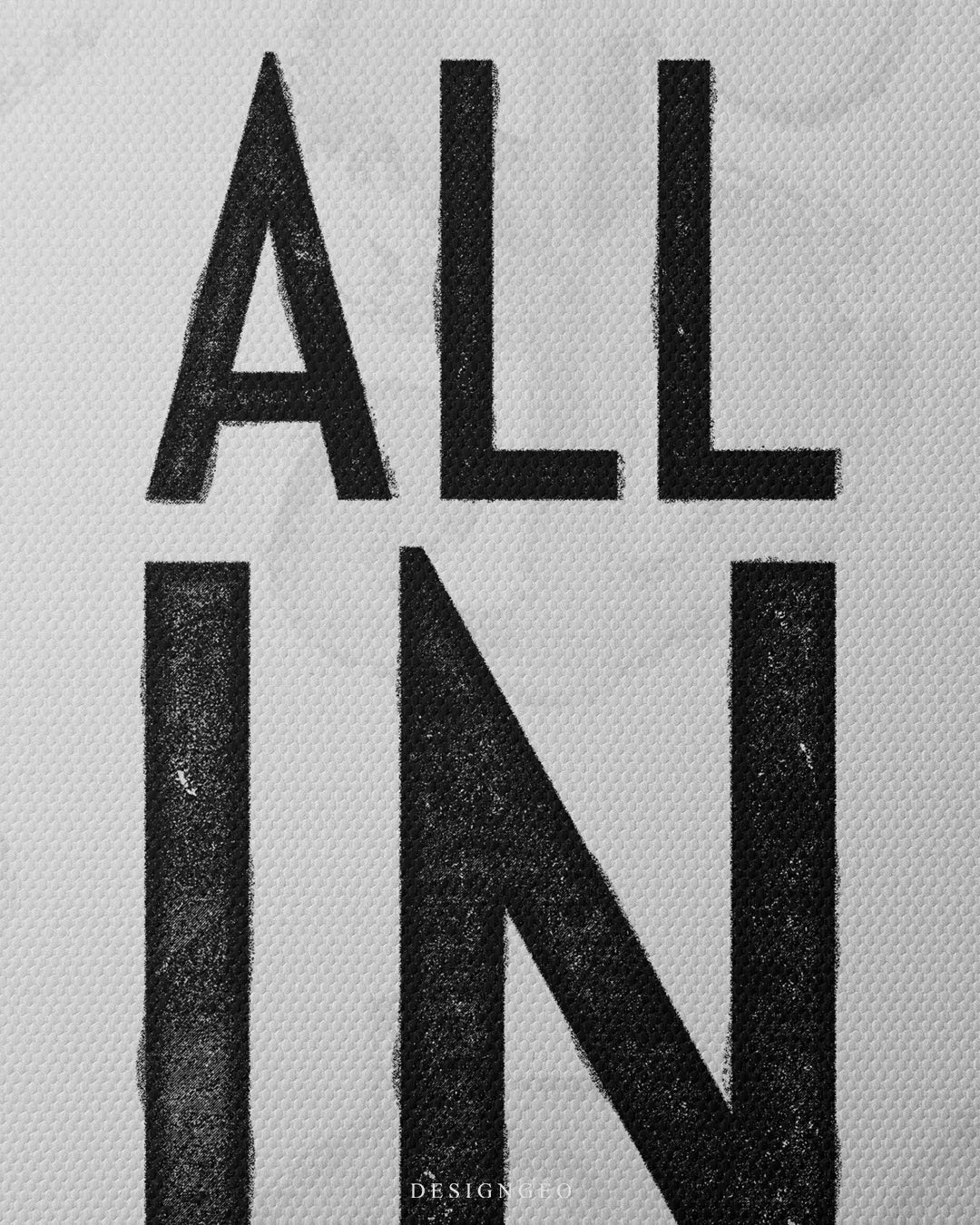 Medium shot showing black stenciled ALL IN typography printed on a white canvas background with subtle watermark patterns