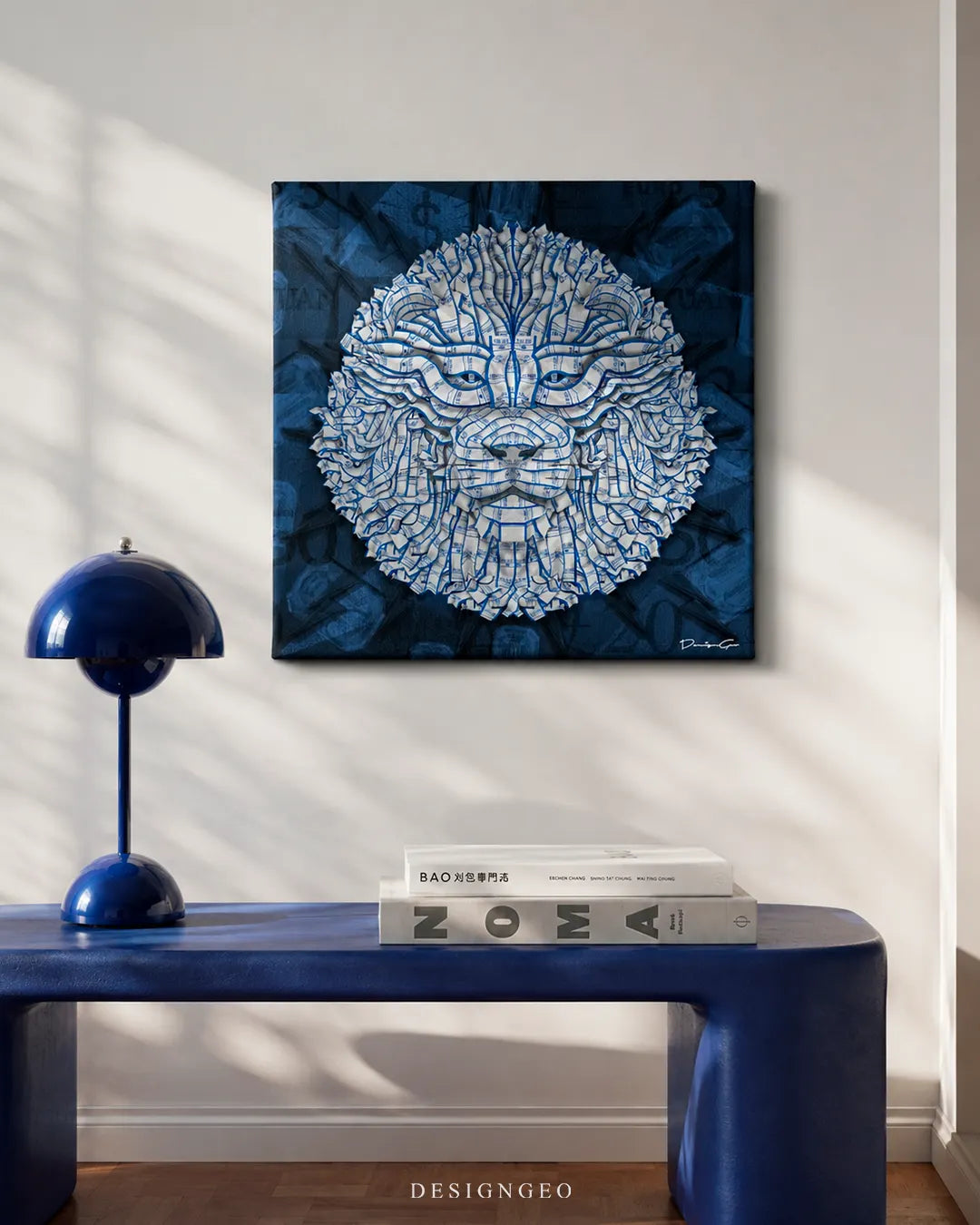 Square Banking Lion canvas wall art mounted on a beige wall above a blue console table with books and a matching blue table lamp