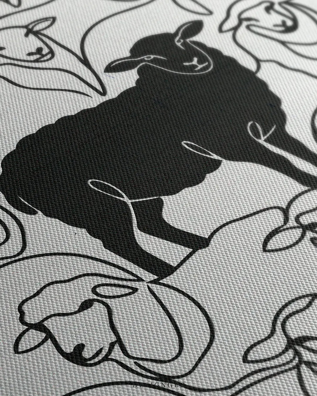 Angled close-up detail shot showing the textured canvas weave, clean black sheep silhouette, and fine fluid line art work