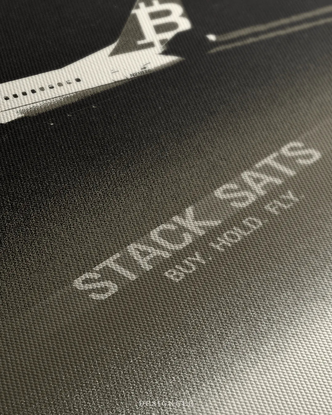 Angled close-up view of the canvas print surface, detailing the airplane tail with the Bitcoin logo and the woven texture over the printed text "STACK SATS BUY. HOLD. FLY."