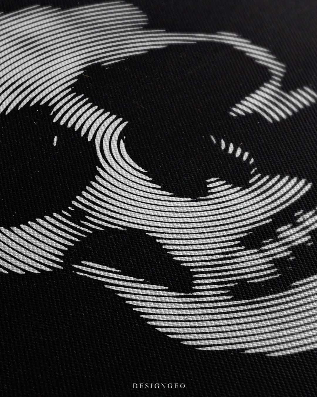 Angled close-up detail shot highlighting parallel white contour lines forming the skull design, deep black ink contrast, and fine woven canvas fabric texture