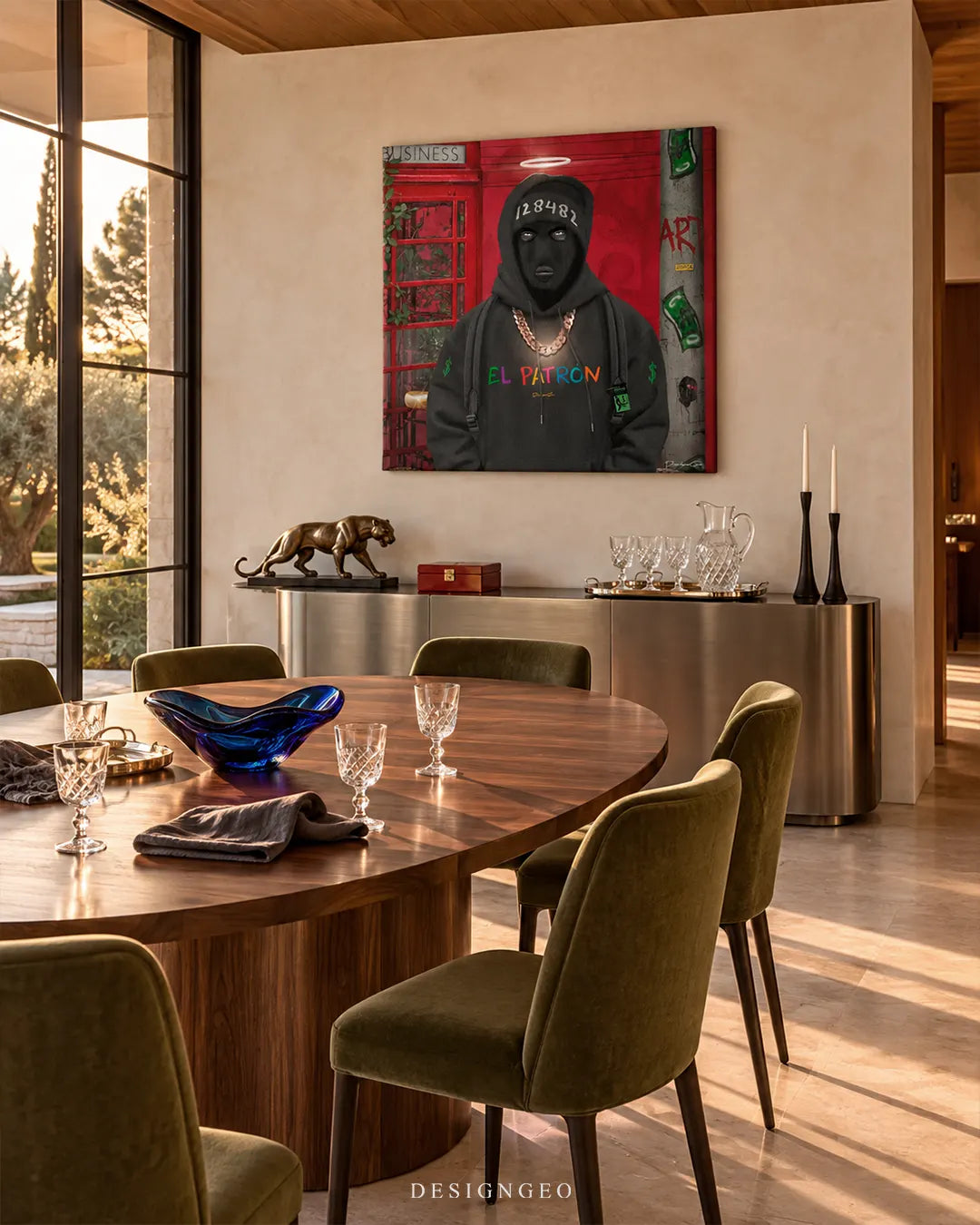 Square canvas print featuring a masked monkey in a black EL PATRON hoodie and gold chain mounted on a beige wall in an upscale dining room above a silver console table