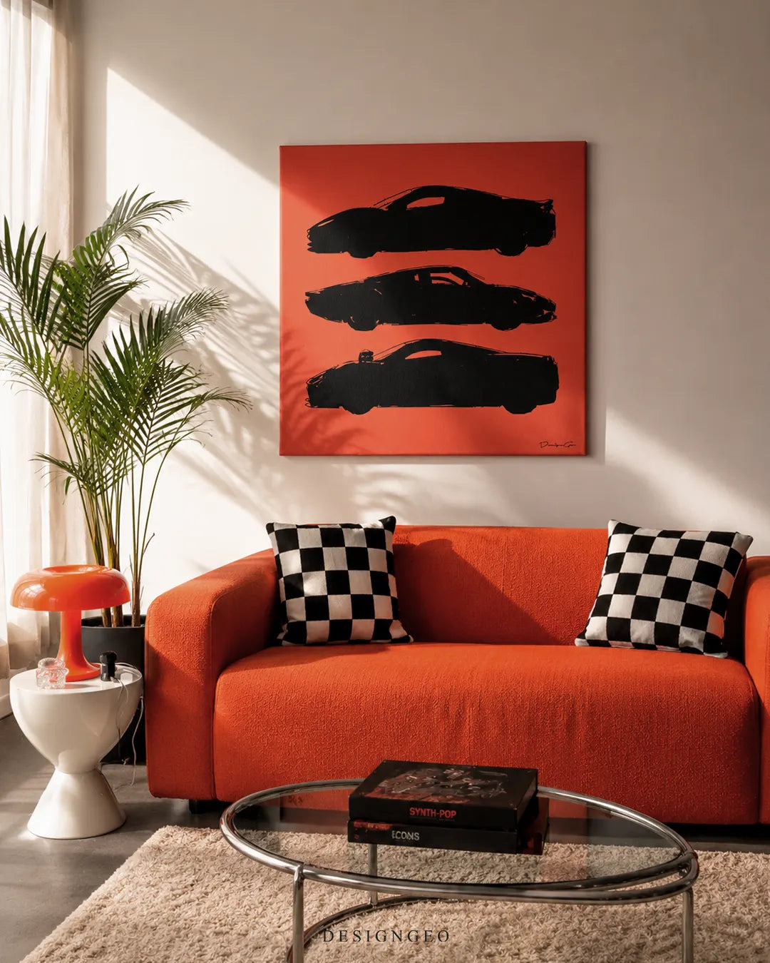 Square orange supercar silhouette canvas print mounted on a neutral wall above a vibrant orange sofa with checkered pillows, a potted palm tree, orange mushroom lamp, and glass coffee table