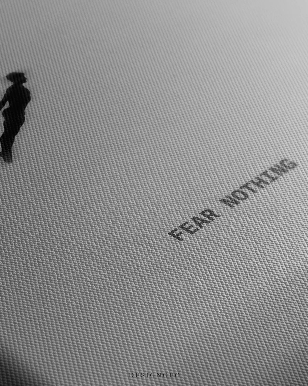 Angled detailed macro texture of fine woven canvas print showing cliff diver silhouette in mid air jump with Fear Nothing quote