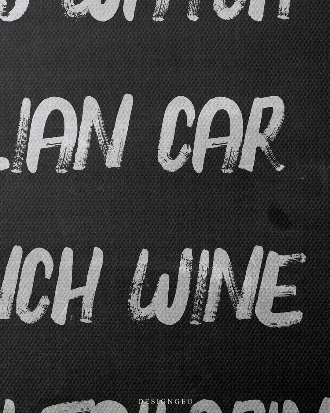 Detailed macro view highlighting the woven black canvas fabric and tactile white paint texture of the words Italian Car and French Wine