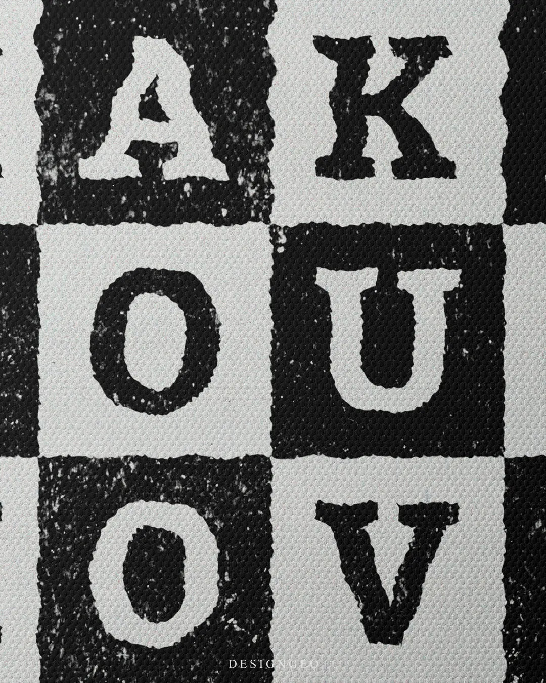 Medium shot highlighting the distressed black and white checkered grid pattern with individual letters A K O U O V printed inside alternating squares