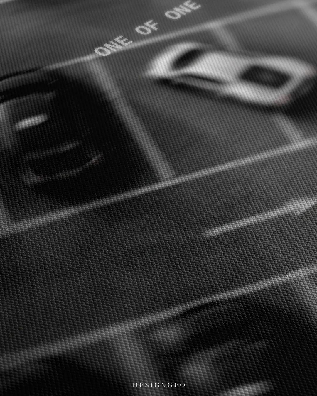 Angled detailed macro texture of dark woven canvas print showing white sports car parked among black cars with One Of One quote