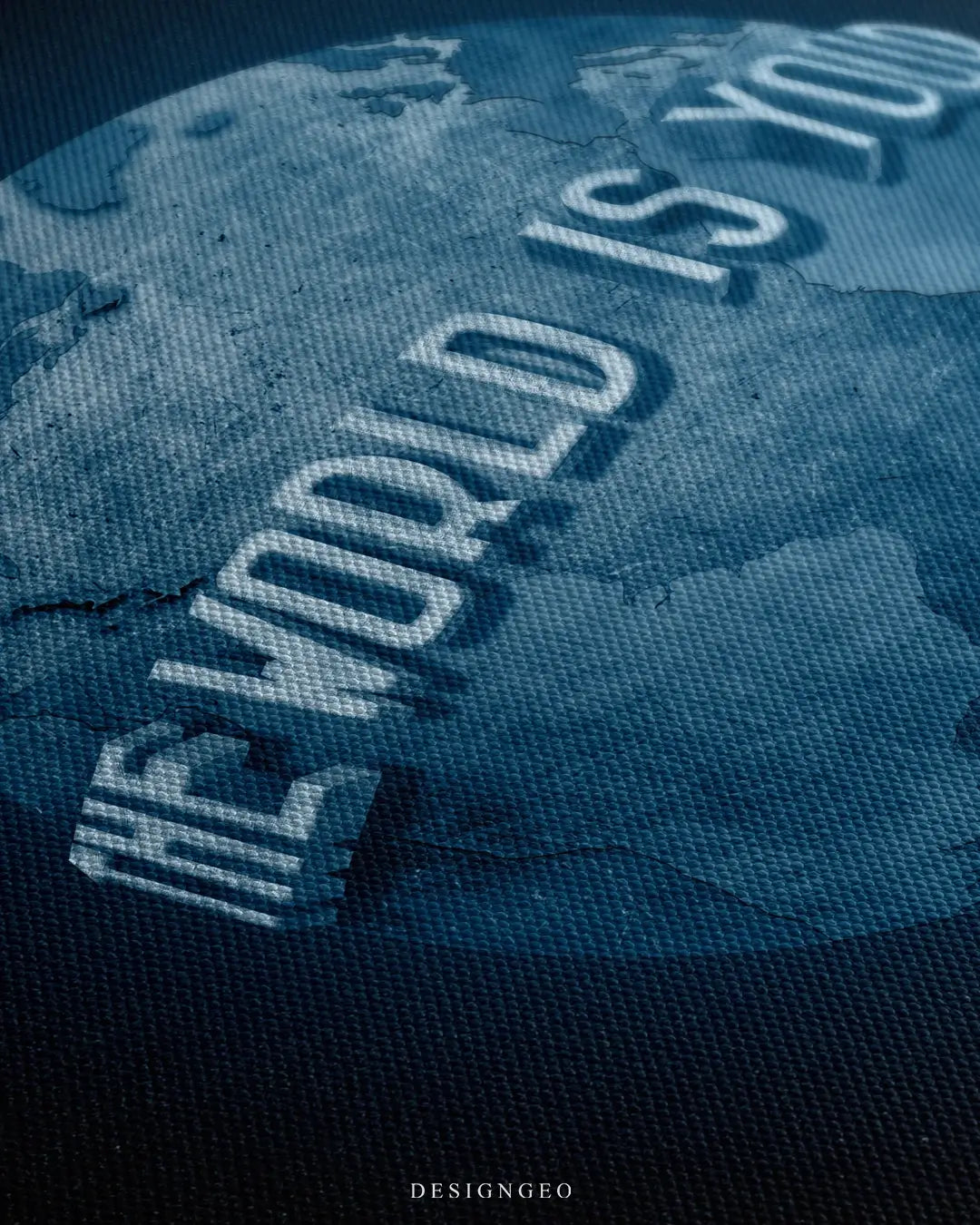 Close-up of motivational wall art featuring a detailed globe with the iconic phrase The World Is Yours in elegant typography on a solid black background