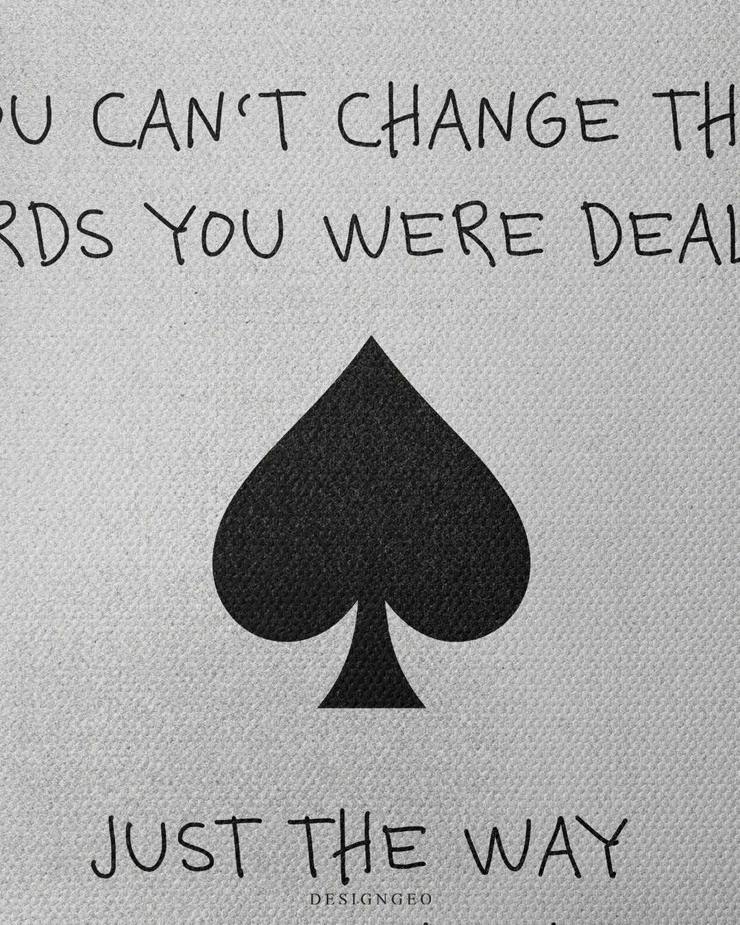 Medium shot close-up highlighting a large black central spade suit icon surrounded by handwritten quote typography on a textured light gray canvas background
