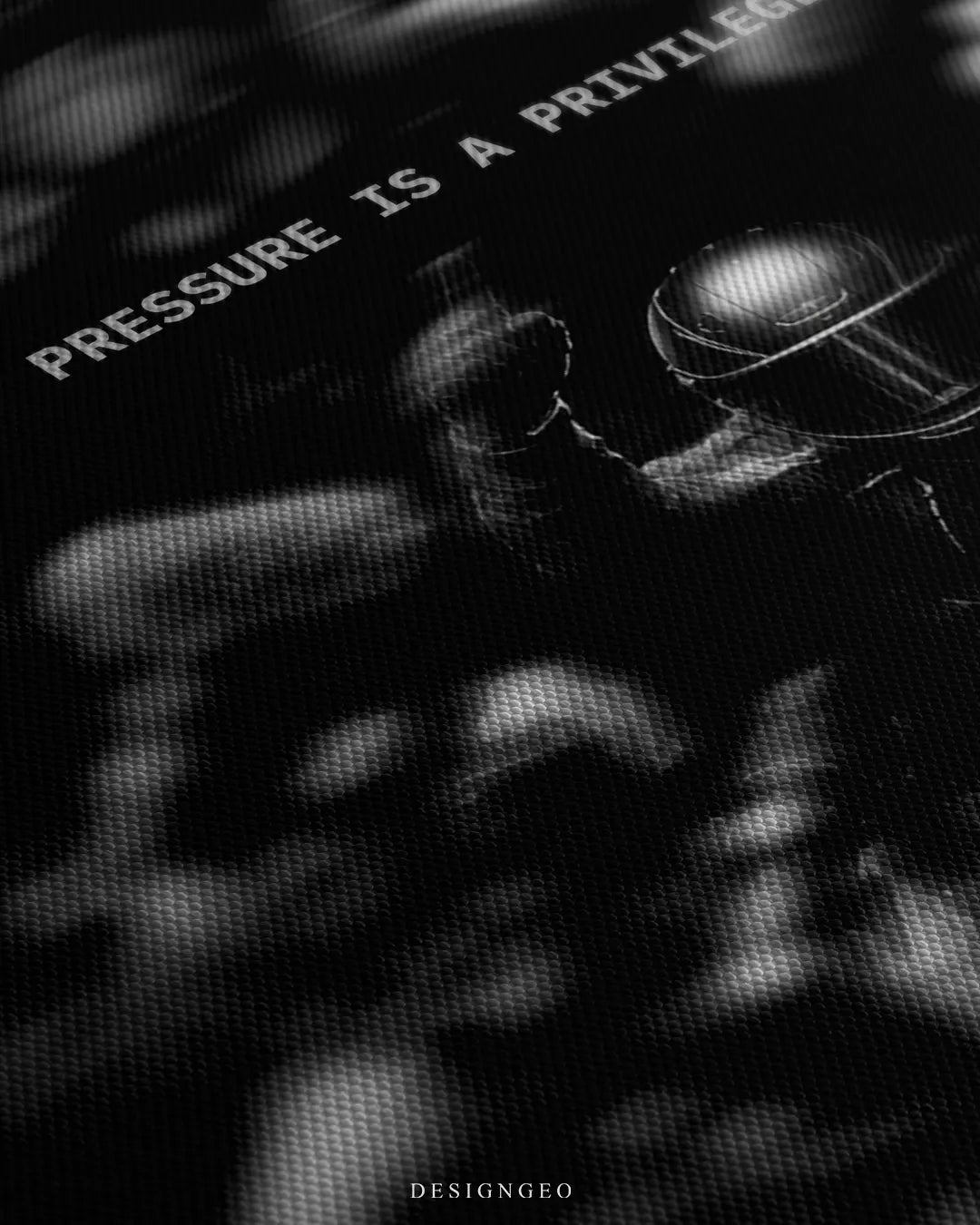 Angled detailed macro texture of black woven canvas print showing racing driver raising fist amidst press microphones with Pressure Is A Privilege quote