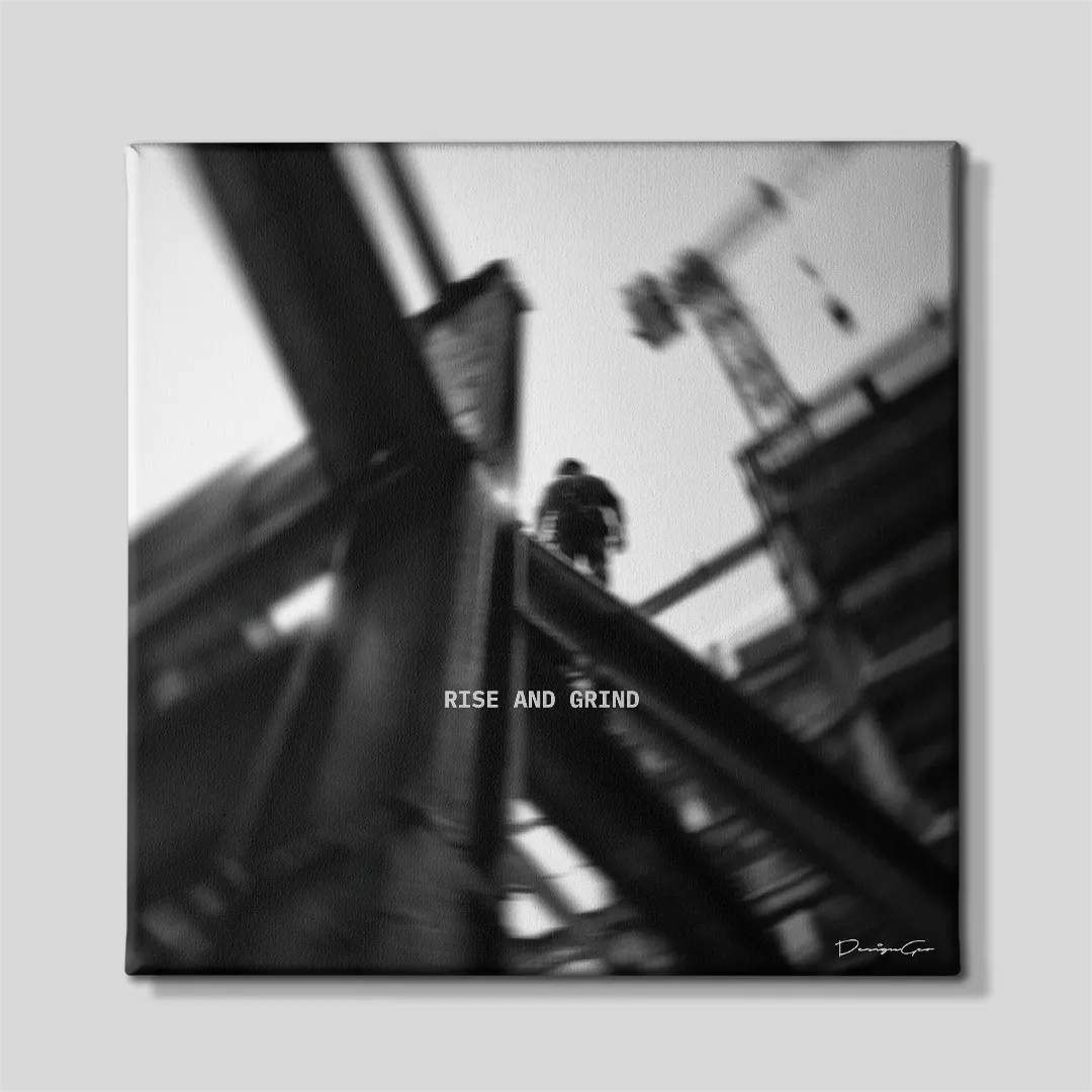 Black and white square inspirational canvas wall art featuring a construction worker walking on steel beams at high altitude under quote Rise And Grind 0.75 inch thin wrap