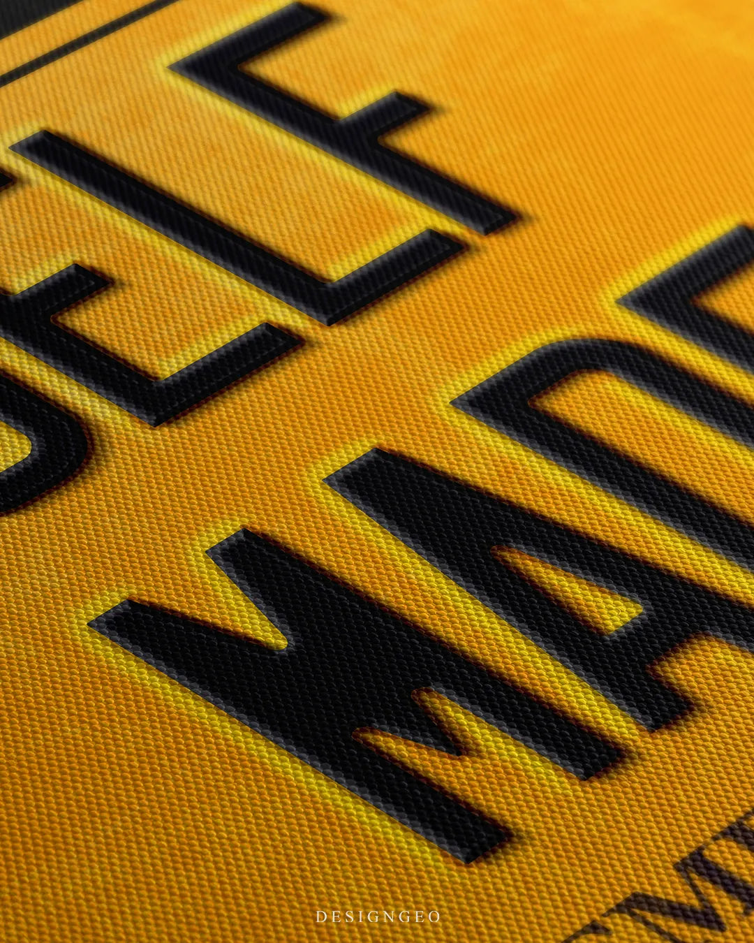 Angled close-up detail shot highlighting the raised black embossed SELF MADE letters, yellow plate surface, and fine woven canvas fabric grain