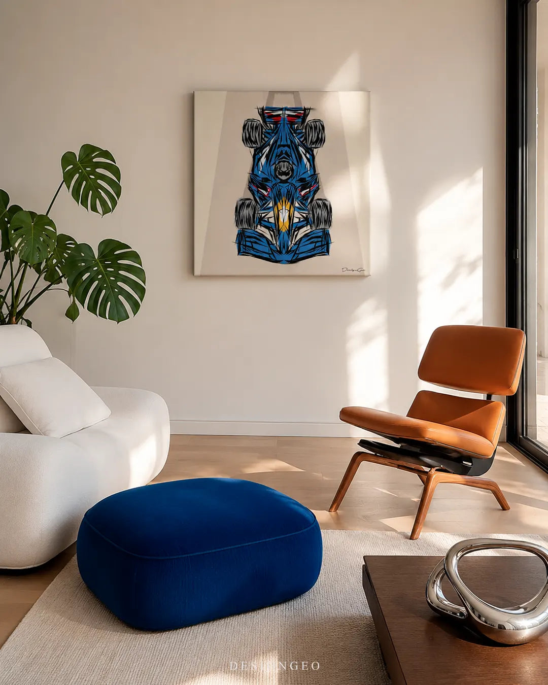 Square blue single-seater race car canvas print mounted on a white wall in a modern living room above a royal blue velvet ottoman, cognac leather lounge chair, and white sofa
