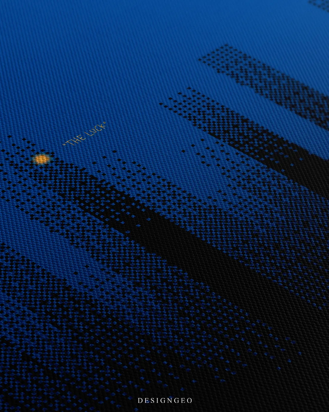 Angled macro view showing fine woven canvas fabric texture, pixelated dark blue skyscraper silhouette, and small yellow text reading THE LUCK