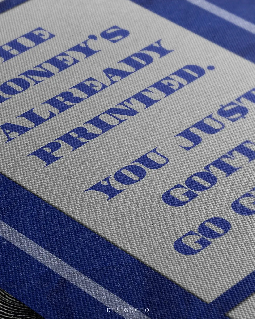 Close-up of motivational money art featuring a stack of US Dollar (USD) banknotes in blue and green tones with the phrase "The money is already printed" in bold blue typography on a white background
