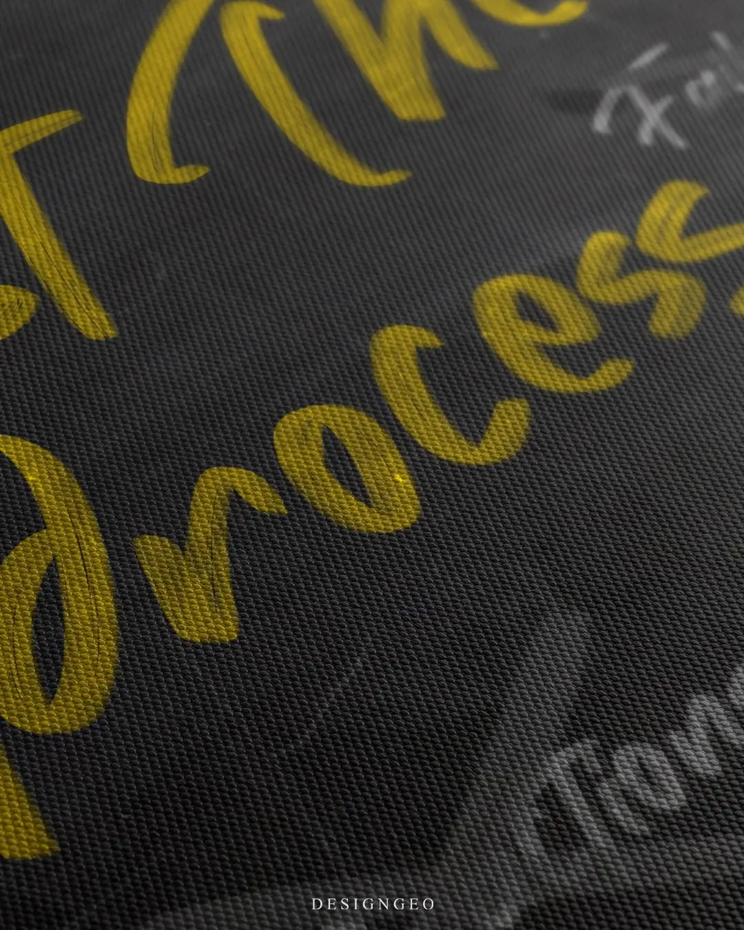 Close-up of minimalist wall art featuring the phrase Trust The Process written in realistic white chalk on a textured black chalkboard background