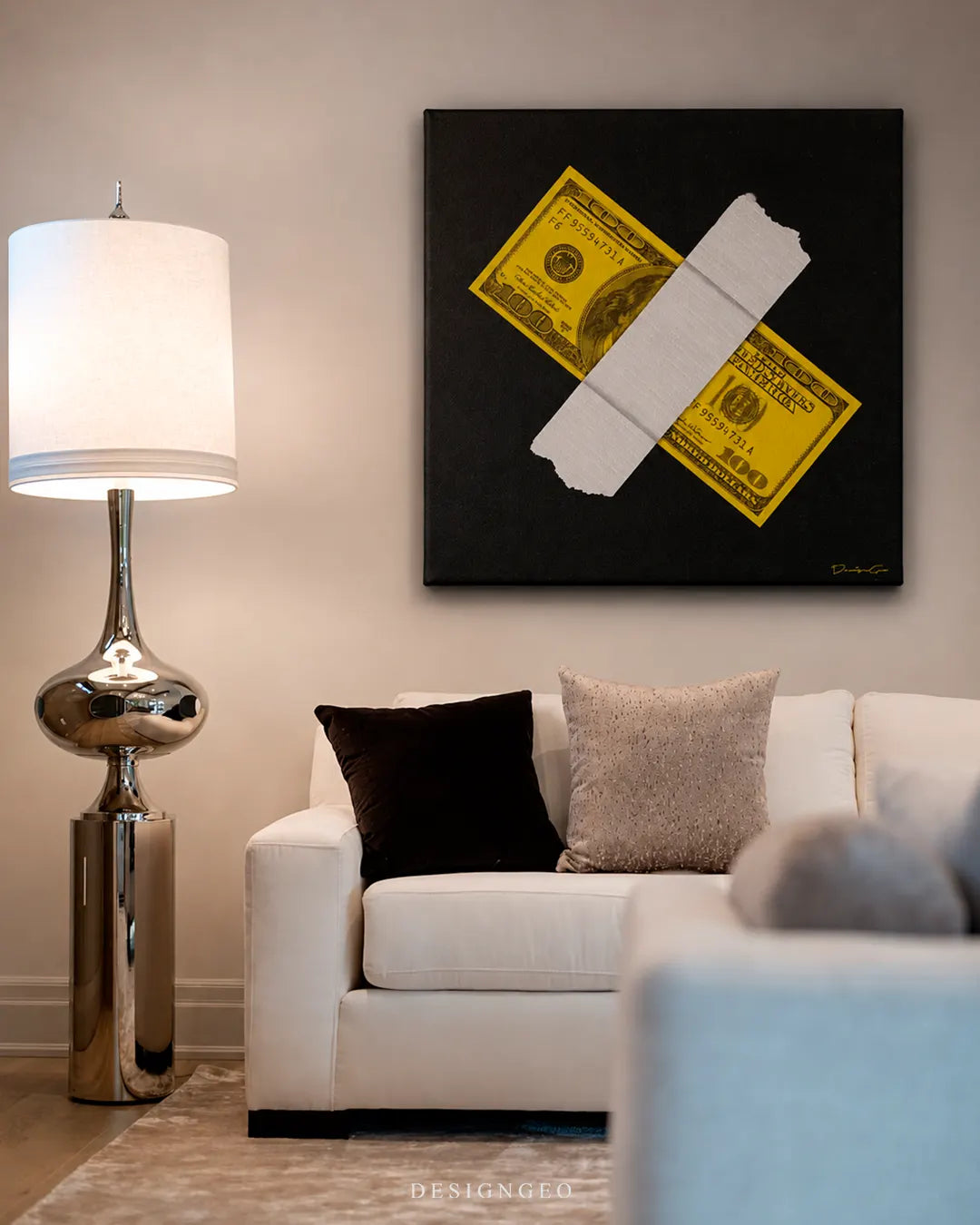 Modern luxury living room setup featuring a square black canvas print of a yellow 100 dollar bill taped with duct tape mounted above a white sofa and beside a floor lamp