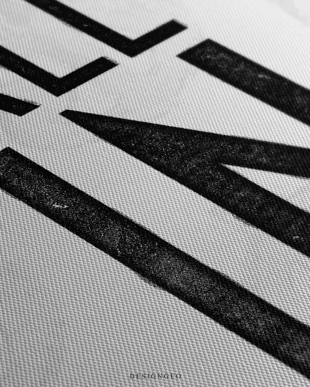Extreme macro detail shot highlighting the textured canvas material and black ink grain on the letter N of the All In print