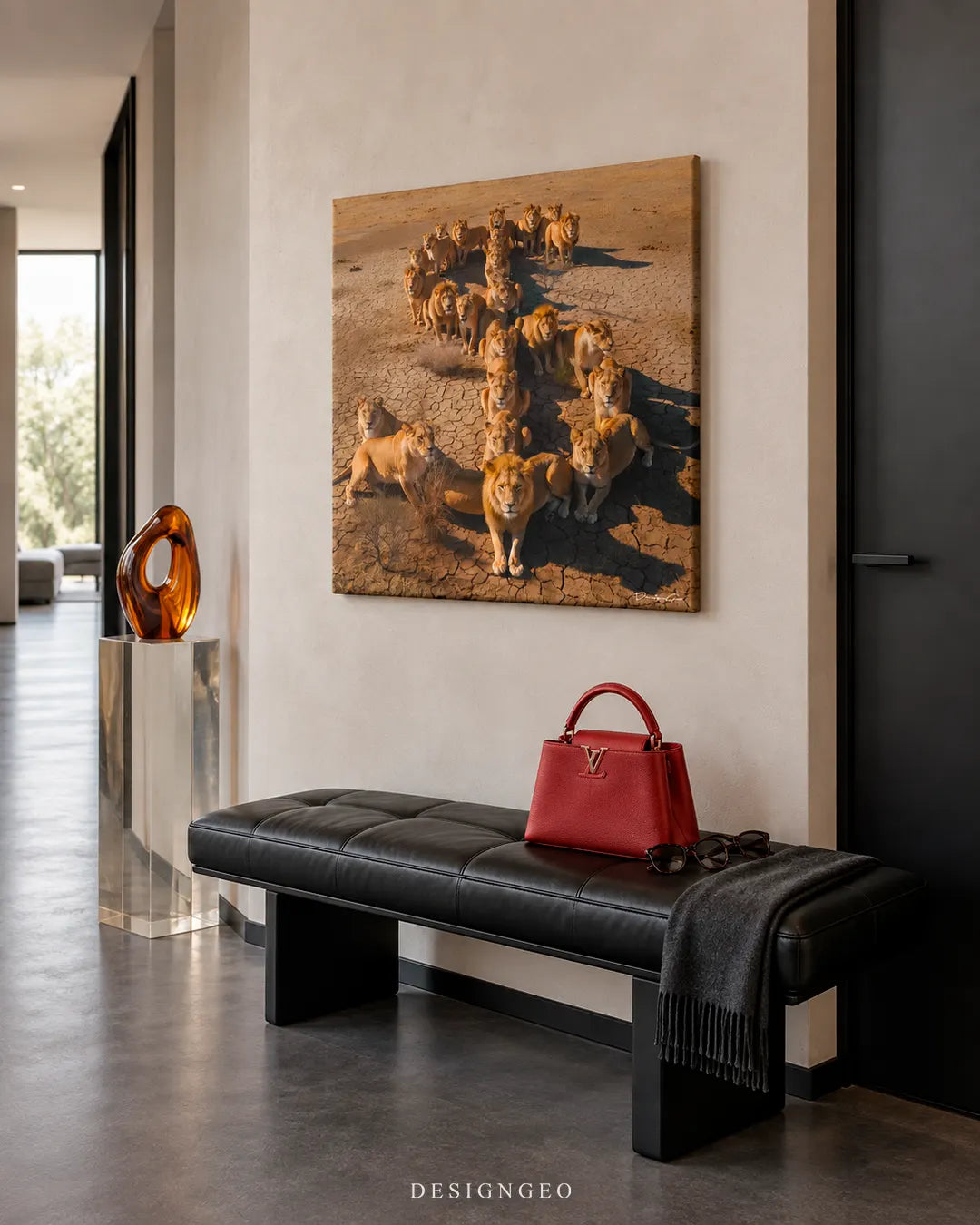 Modern luxury hallway entryway featuring a square canvas print of a lion pride walking in an arrow formation across dry savanna ground mounted on a beige wall above a black leather bench