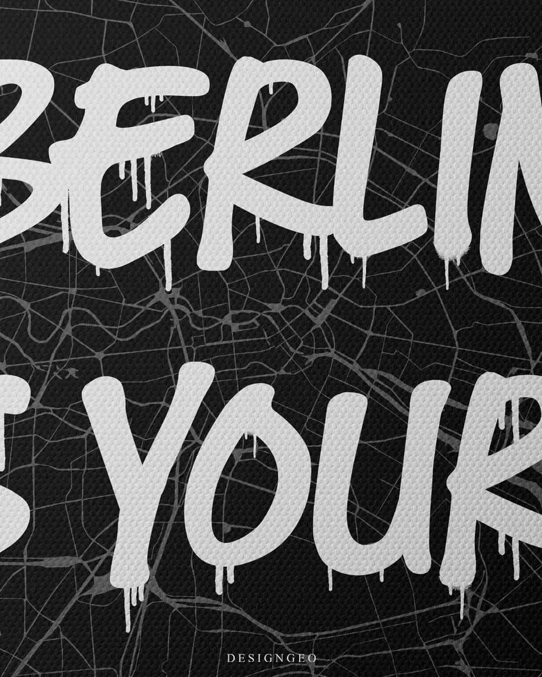 Close-up of minimalist urban wall art featuring a detailed Berlin city map layout with the motivational phrase "Berlin is Yours" in striking white graffiti typography on a dark background