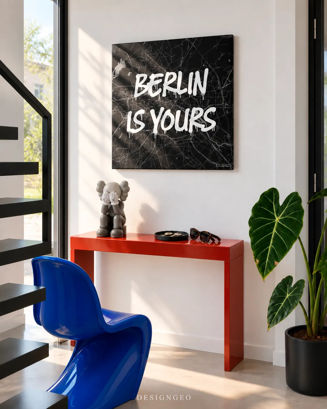 Modern luxury hallway featuring a square canvas print of a black and white Berlin street map with white graffiti text BERLIN IS YOURS mounted above a red console table