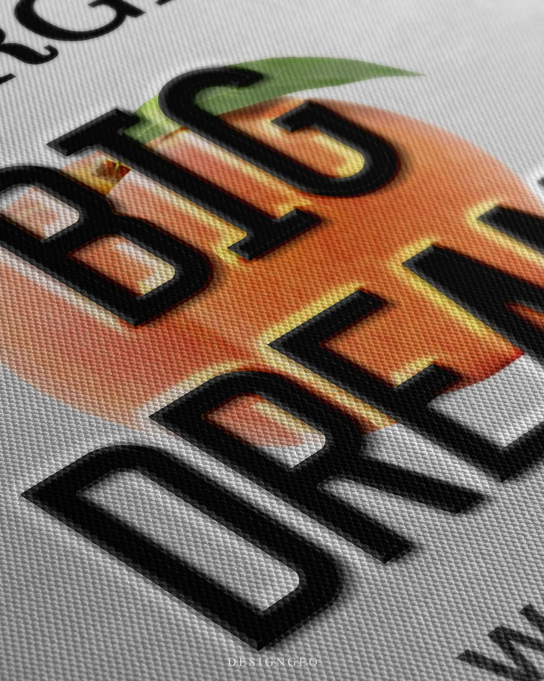 Angled close-up detail shot highlighting the 3D black embossed BIG DREAMS letters, vibrant peach illustration, subtle warm glow, and fine woven canvas fabric texture