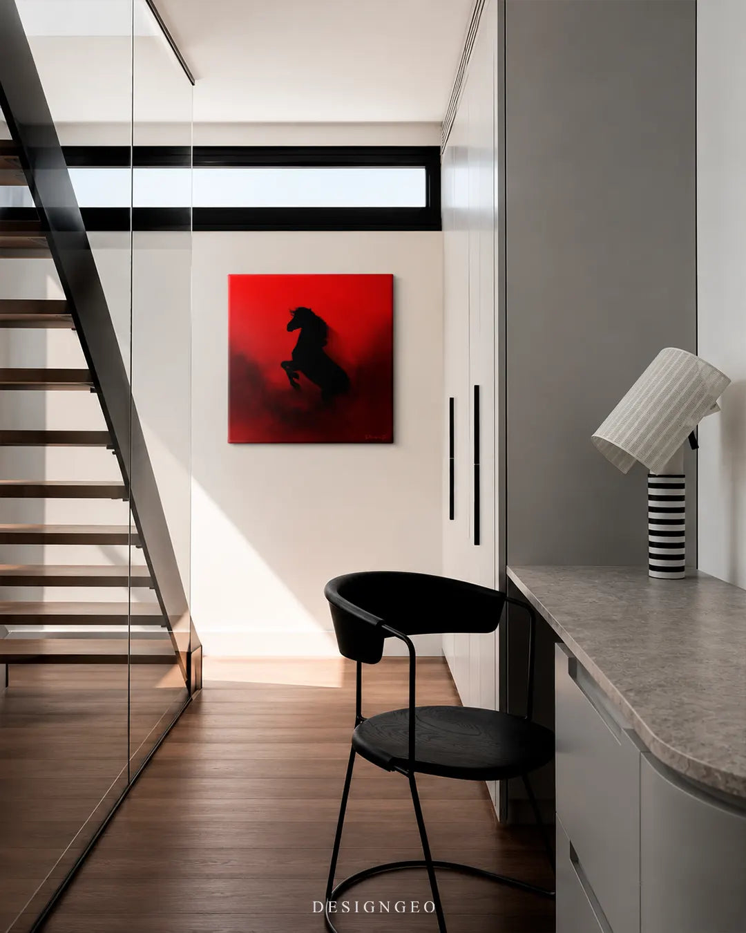 Square black horse red background canvas wall art mounted on a off-white wall in a modern minimalist hallway next to a floating wooden staircase and sleek desk chair