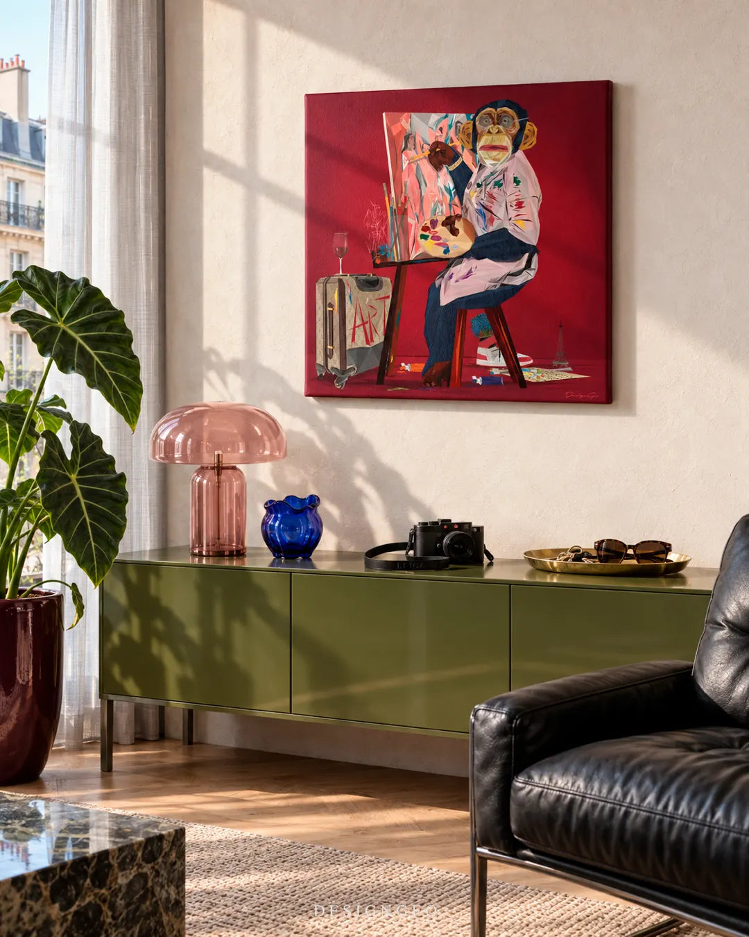 Cubist chimpanzee painter square canvas art mounted above an olive green credenza in a sunlit modern living room next to a indoor plant