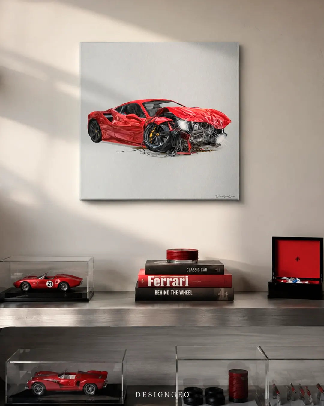 Square crashed red sport car canvas print mounted on a beige wall above a metallic console shelf with car art books, diecast scale model cars in display cases, and a red box