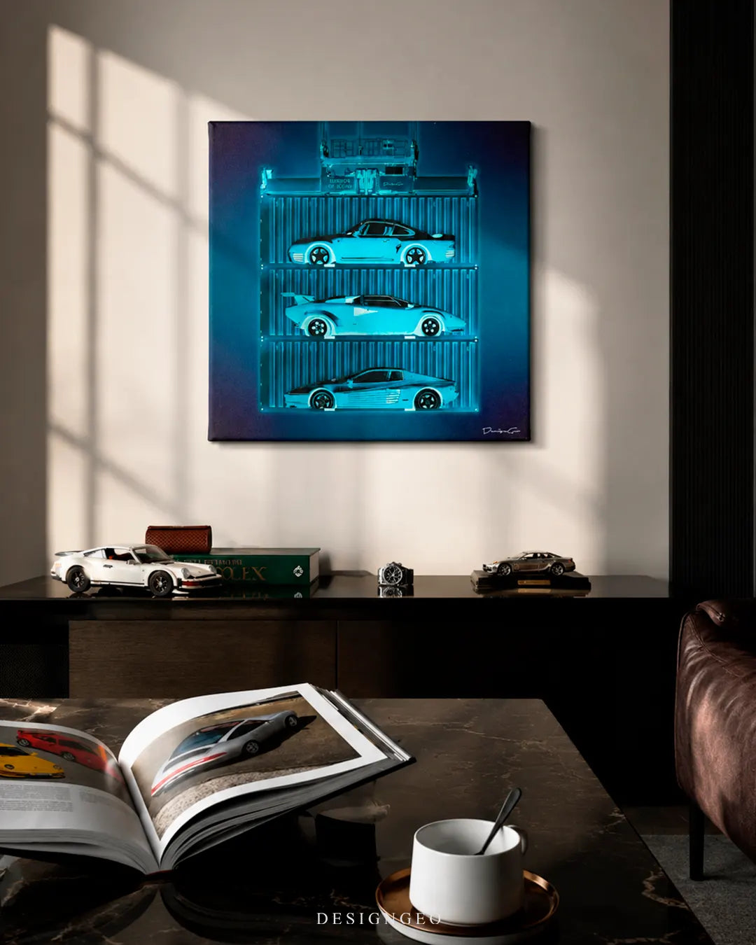 Square Exotics Container canvas print mounted on a beige wall above a dark wooden credenza with a white Porsche 911 scale model, Rolex book, luxury watch, and open supercar art magazine on a marble coffee table