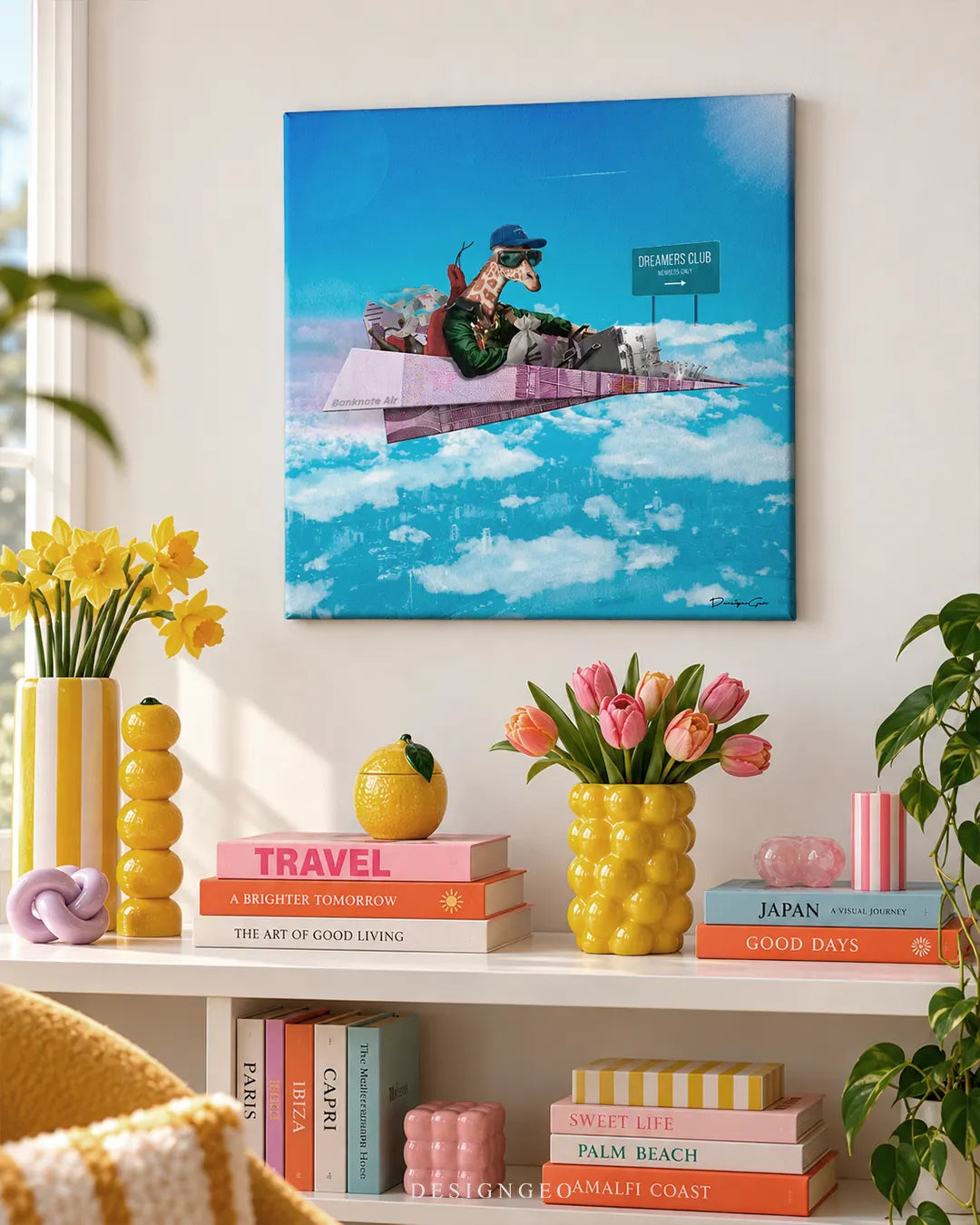 Square blue sky canvas print featuring a cool giraffe flying a pink 500 Euro paper airplane mounted on a white wall above a bright white shelf styled with yellow flower vases and colourful travel books