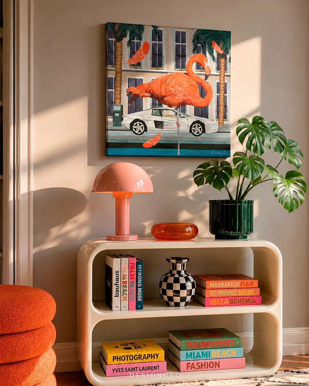 Square pink flamingo French Riviera canvas print mounted above a white retro console table with a pink dome lamp, Monstera plant, and colorful Assouline-style travel books