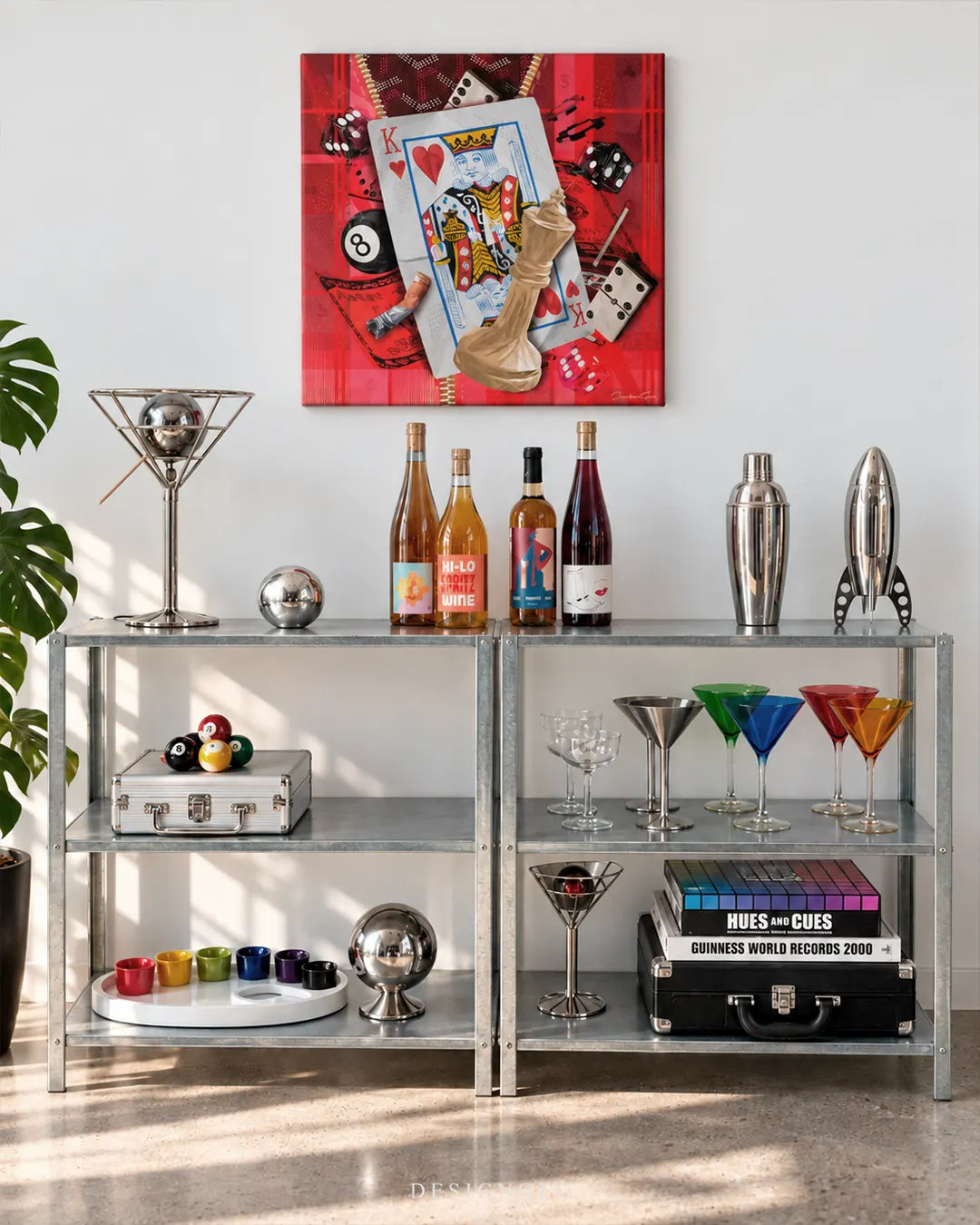 Square red collage canvas print featuring a King of Hearts card, casino dice, dominoes, 8-ball, and a chess piece mounted on a white wall above a industrial metal bar shelf setup