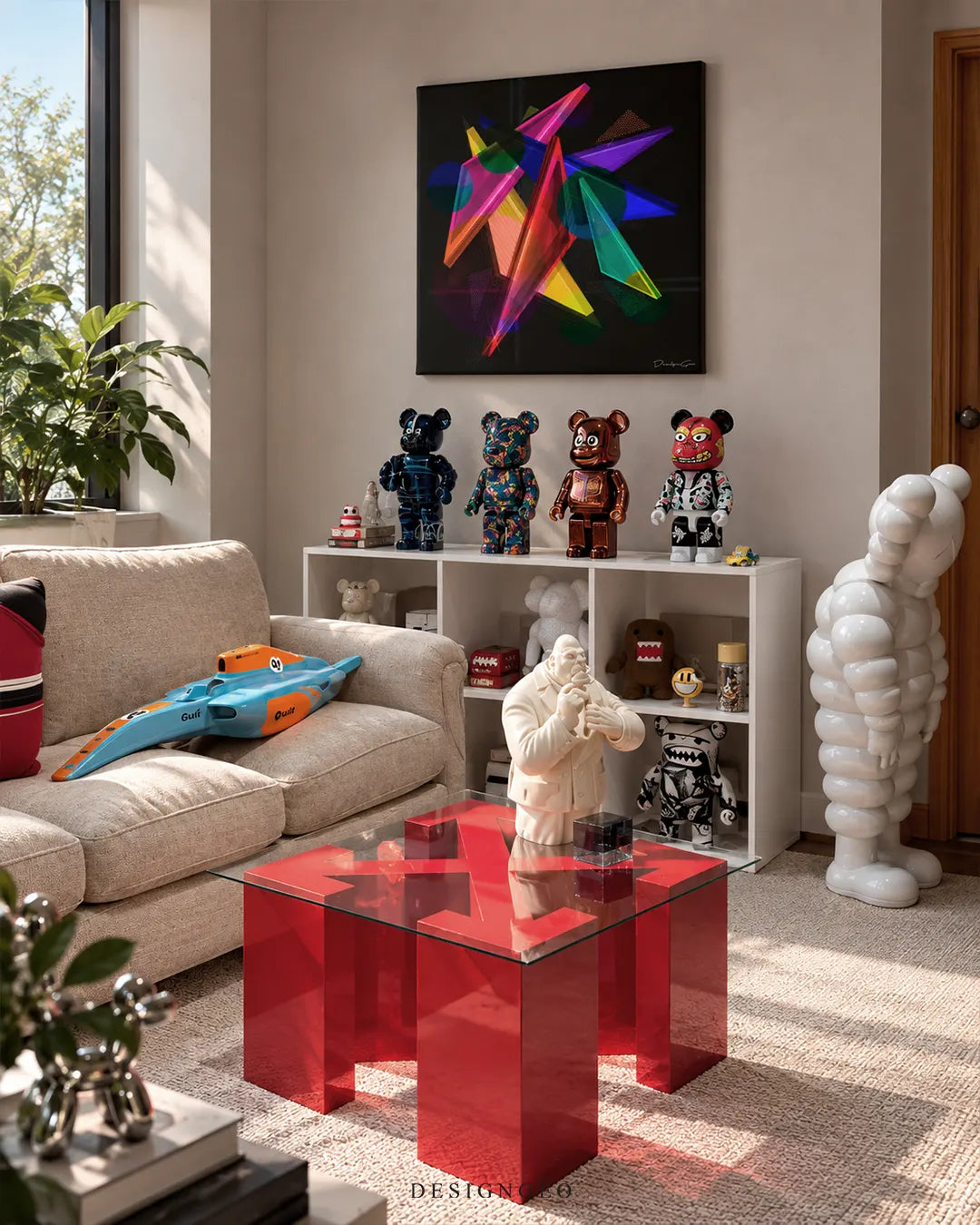 Square black canvas print featuring vibrant colorful abstract geometric shapes mounted on a light beige wall in a modern hypebeast living room above a white shelving unit with collectible art toys and a red glass coffee table