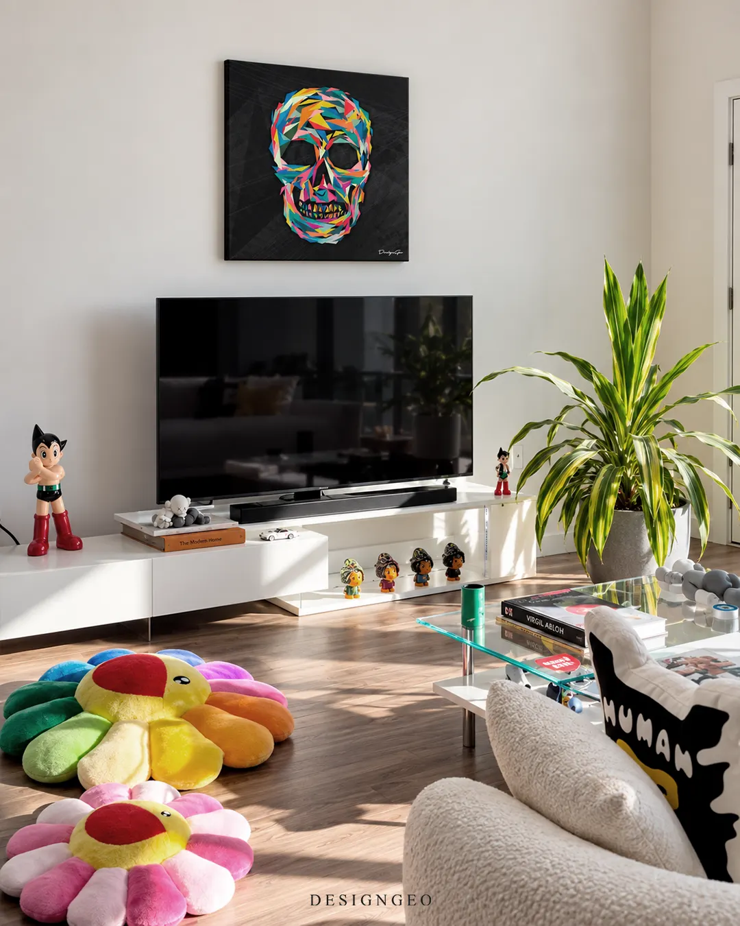Square black canvas print featuring a vibrant colorful geometric low-poly skull mounted on a white wall above a TV stand in a modern hypebeast media room with pop art collectibles and Takashi Murakami style floor cushions