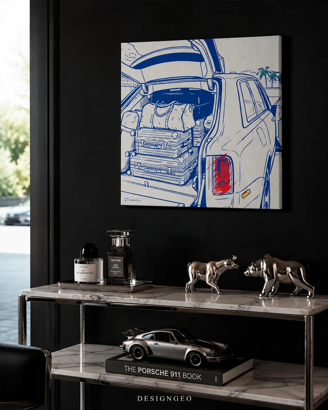 Square luxury SUV trunk blue line art canvas mounted on a matte black wall above a marble console table with silver bull and bear sculptures, perfumes, and a luxury car 911 book