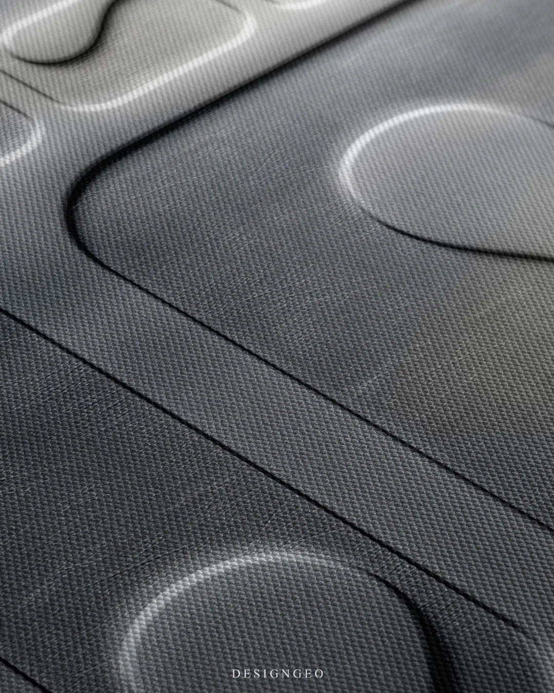 Angled extreme macro view highlighting the woven canvas surface texture, silver gradient shading, and debossed contours of the modern typography
