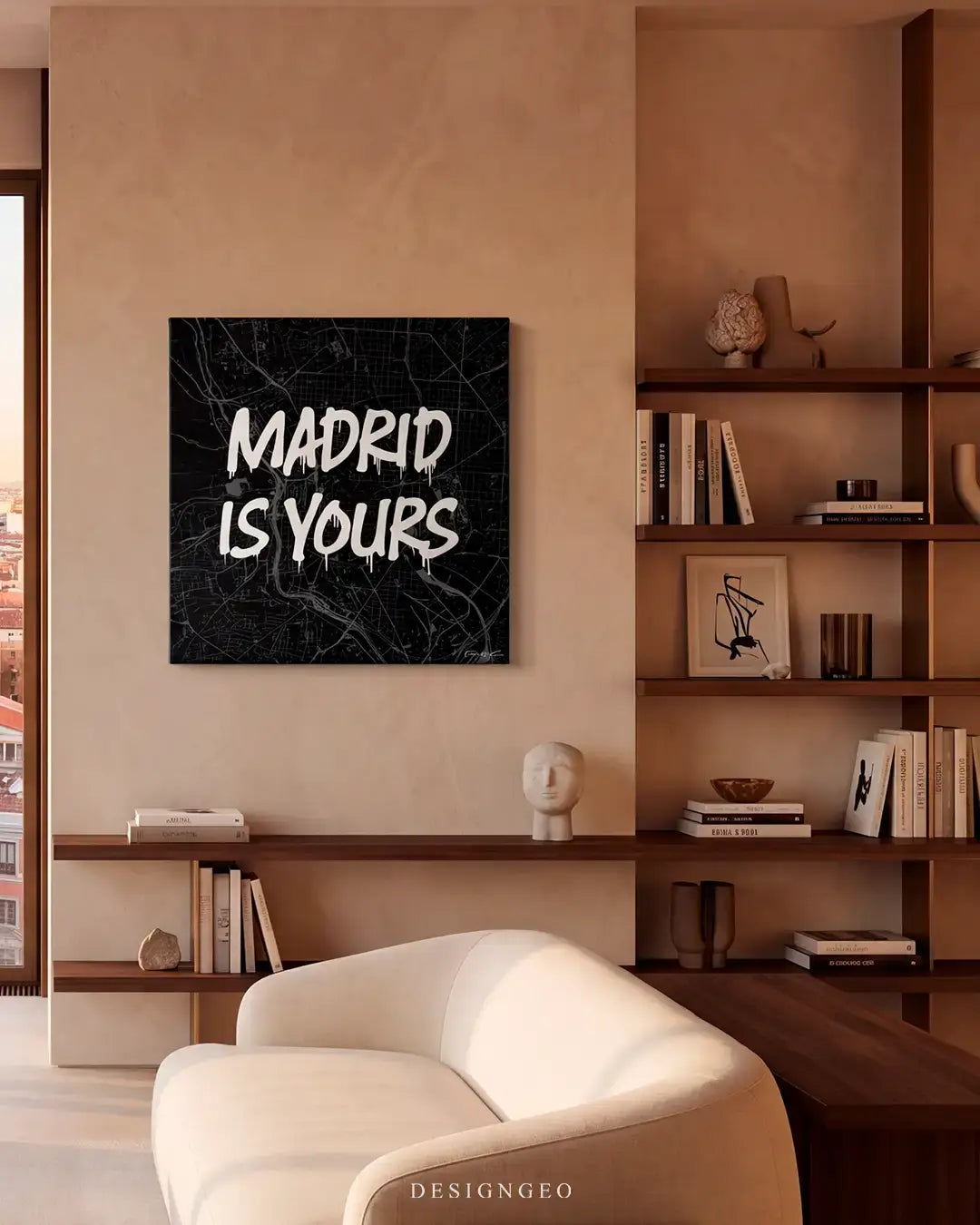 Modern minimalist living room interior with warm lighting, featuring the black and white Madrid city map canvas print mounted on a beige column wall next to a wooden bookshelf