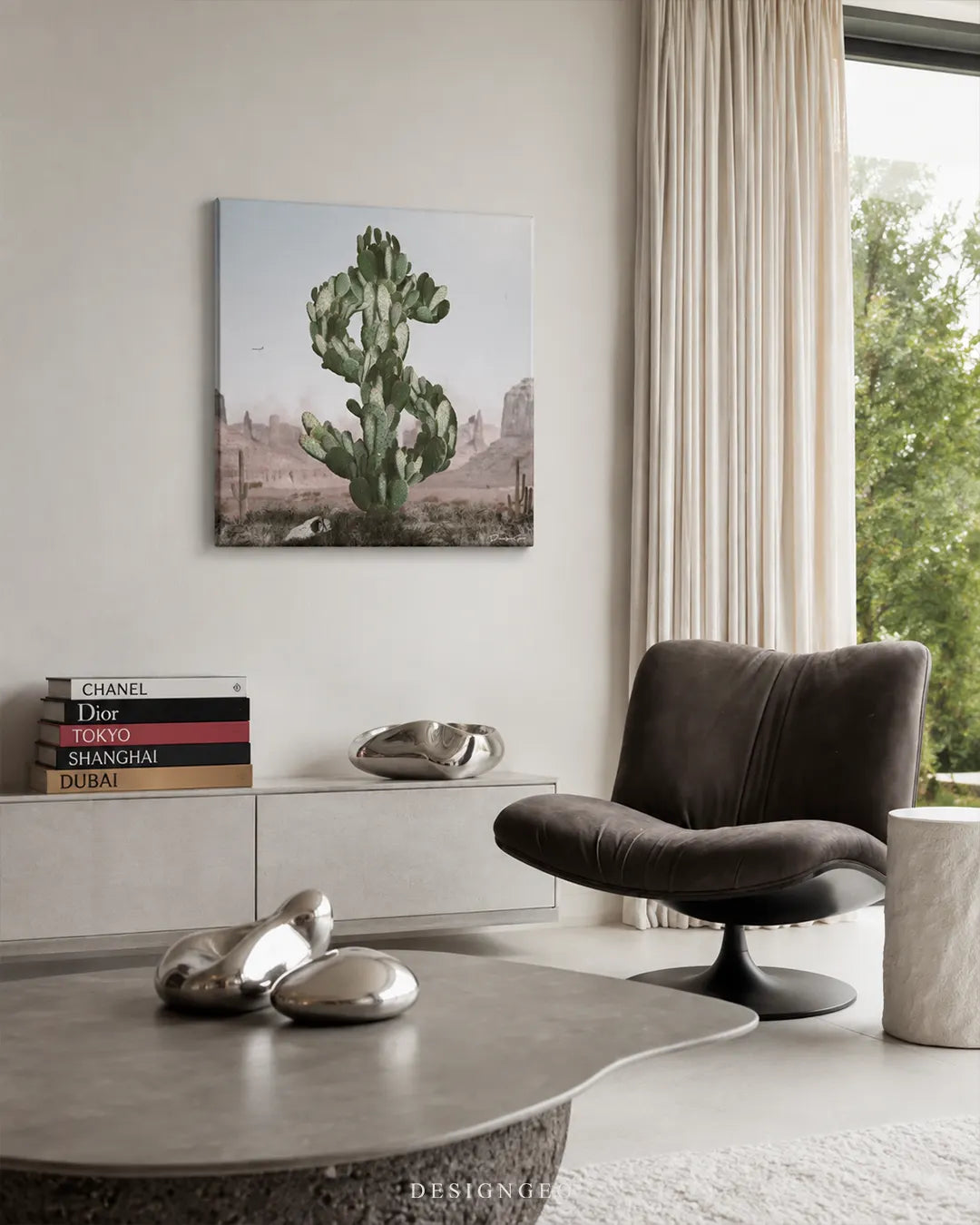 Square dollar sign cactus canvas wall art mounted on a cream wall in a bright modern living room above a white sideboard with fashion books and a swivel chair