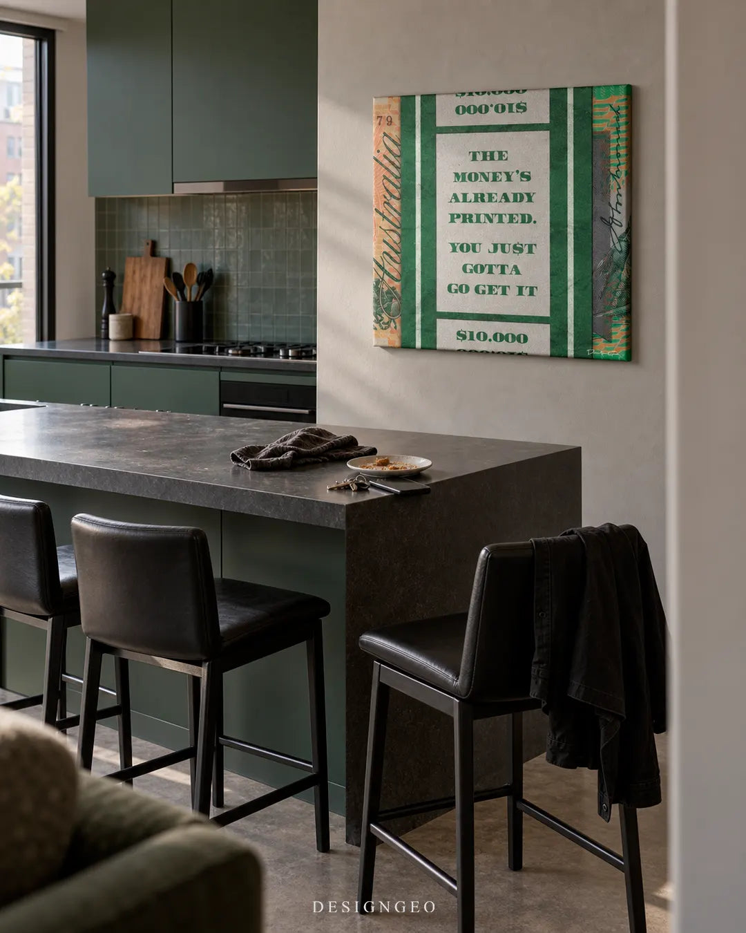 Modern luxury kitchen interior featuring a square canvas print inspired by an Australian dollar note with green motivational text reading THE MONEY'S ALREADY PRINTED YOU JUST GOTTA GO GET IT mounted on a beige wall above a dark island