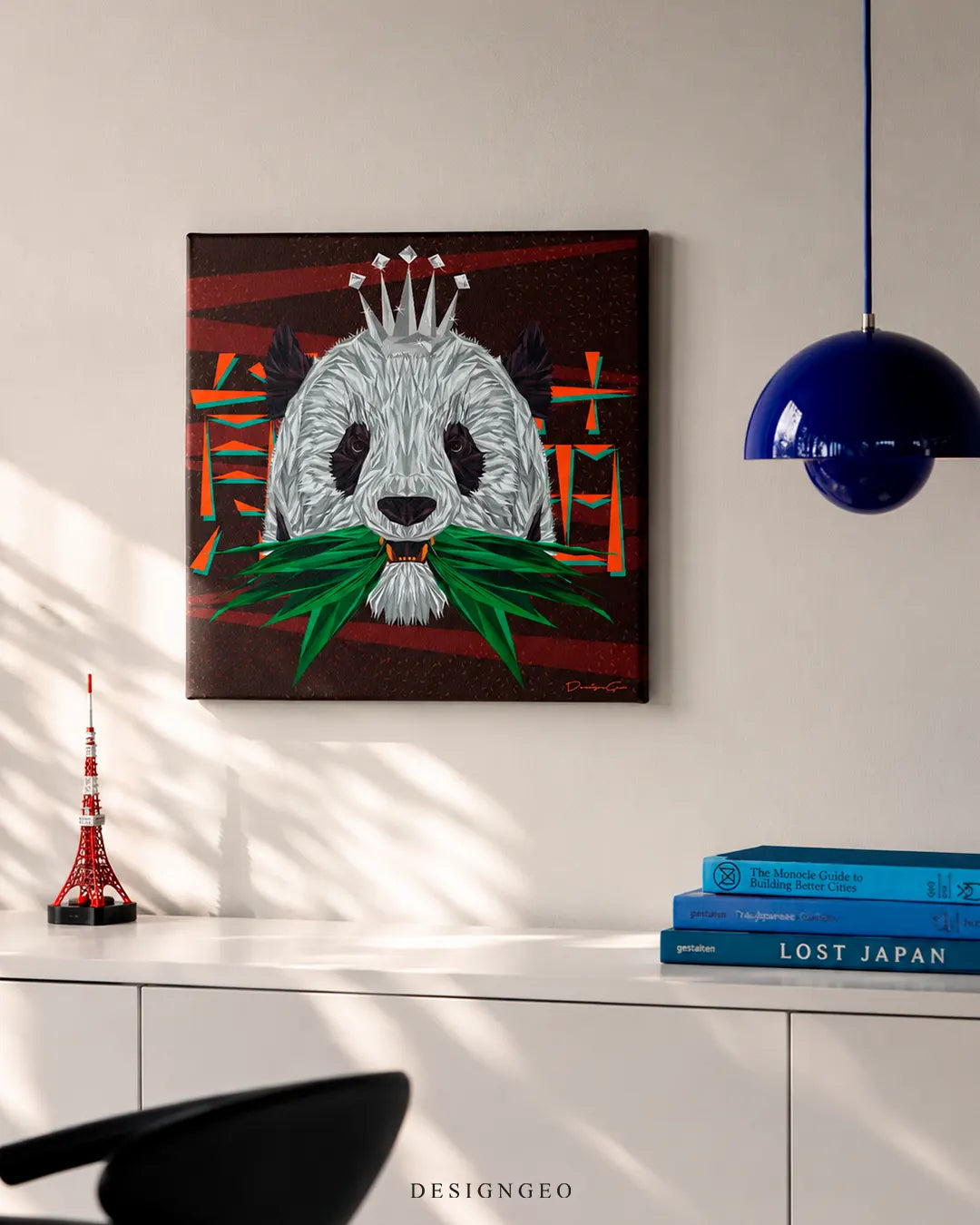 Square Panda King canvas wall art displayed on a white wall above a modern sideboard with books, a miniature Tokyo Tower, and a blue pendant lamp