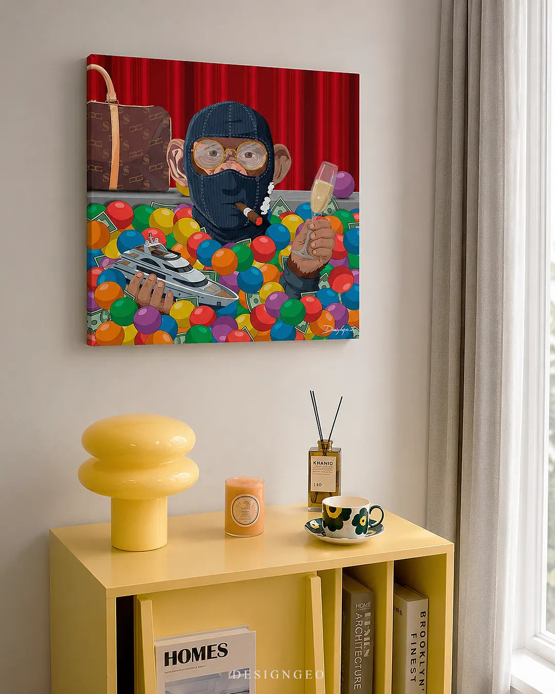 Square Player One monkey canvas wall art displayed on a neutral wall above a yellow modern cabinet with a lamp, teacup, and books