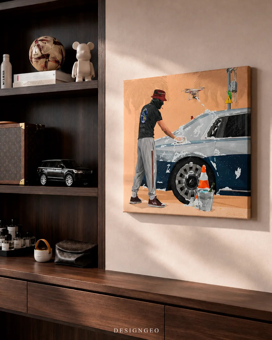 Square Pristine Fleet luxury car wash canvas print mounted on a beige wall next to dark wooden shelving with luxury accessories, a toy car, and designer decor