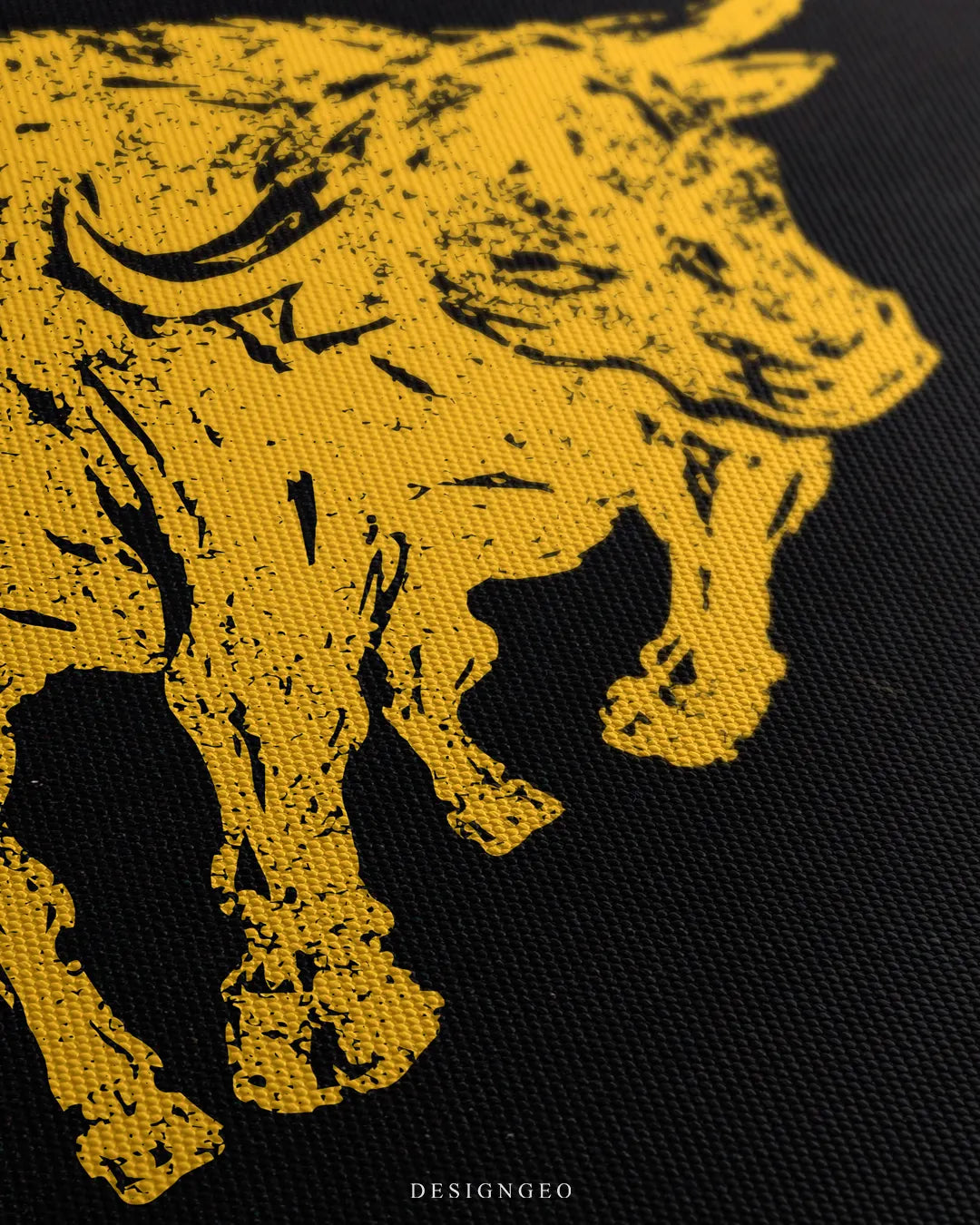 Angled macro shot highlighting the fine woven canvas texture and the detailed yellow distressed print of the bull hooves and body