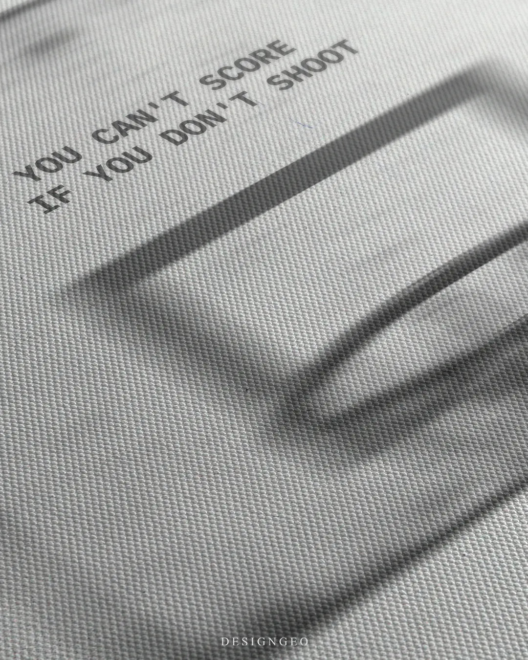 Close-up view of motivational quote YOU CAN'T SCORE IF YOU DON'T SHOOT printed above a motion-blurred basketball backboard and hoop on canvas texture