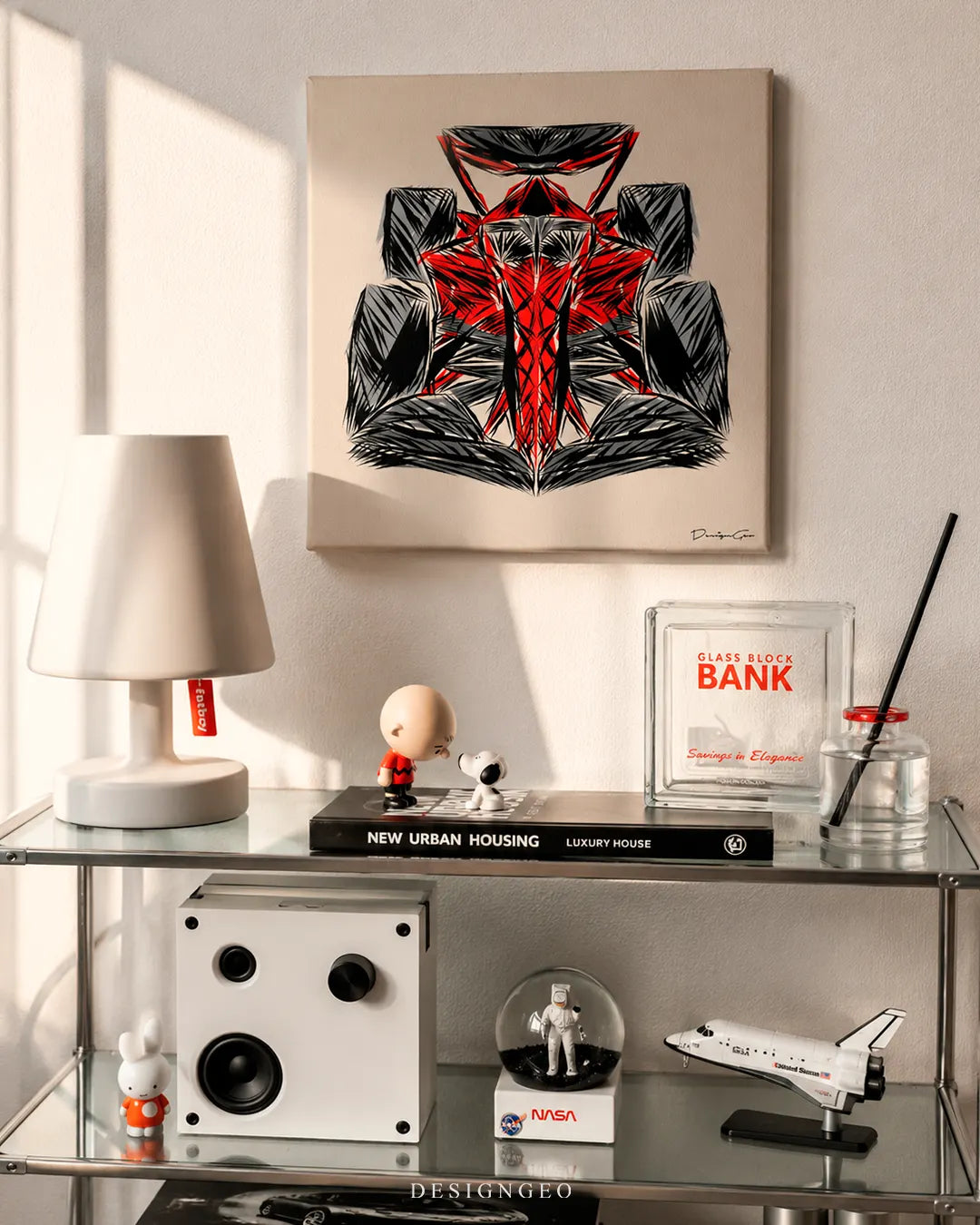 Square beige F1 crayon sketch canvas print mounted on a white wall above a glass shelf with a Fatboy table lamp, Snoopy figure, and NASA space shuttle toy