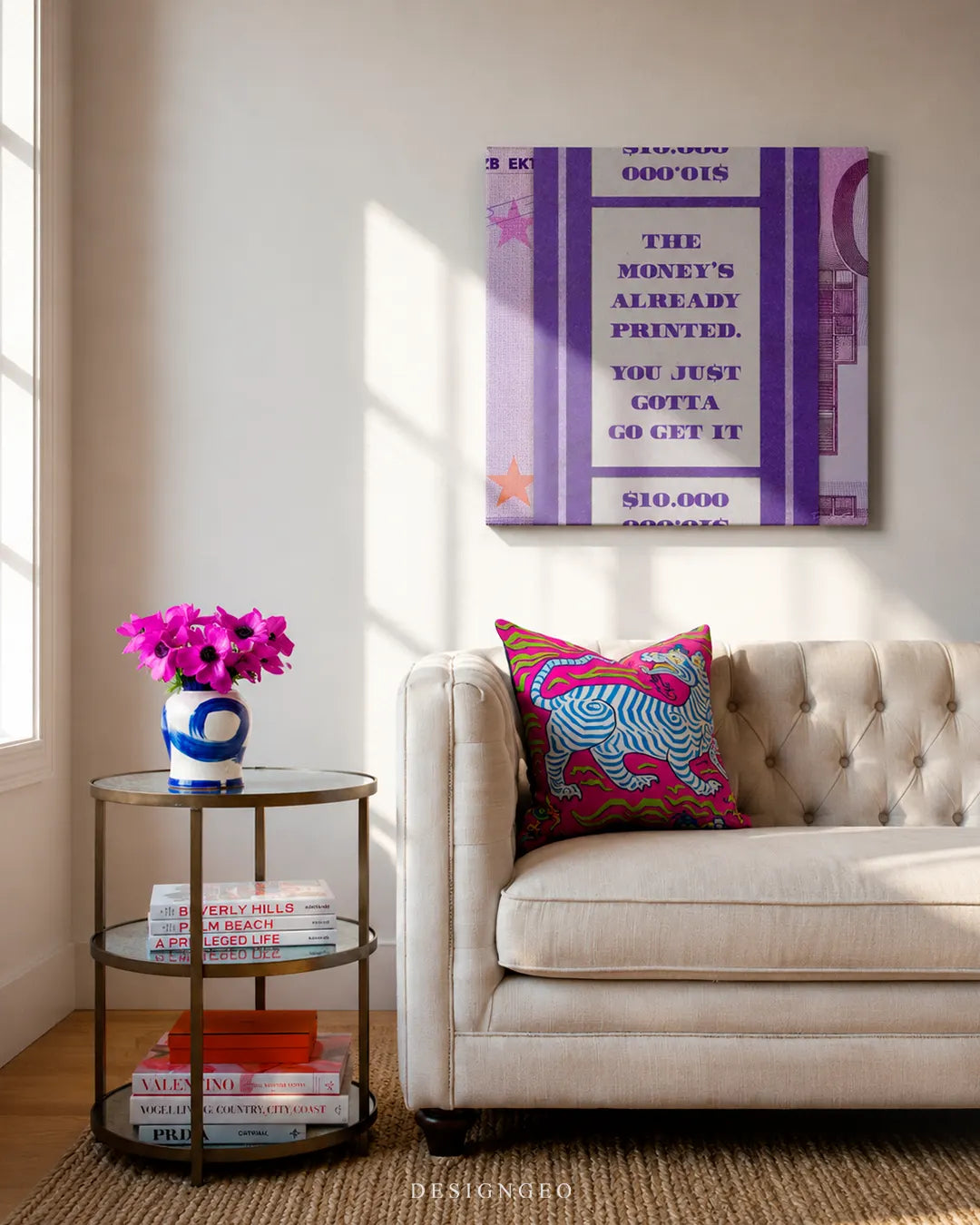 Vertical purple Euro banknote canvas wall art mounted on a beige wall above a cream tufted sofa with a colorful pillow and a round glass side table